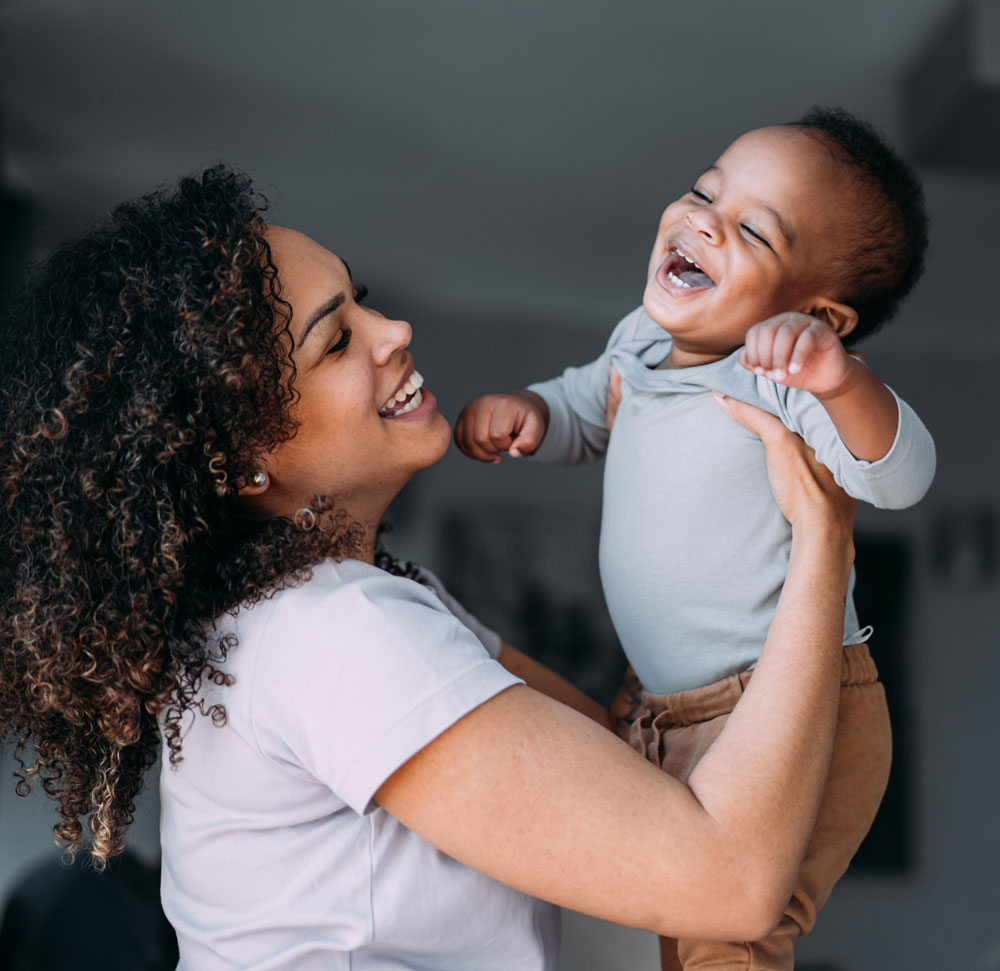 mother lifting laughing baby up