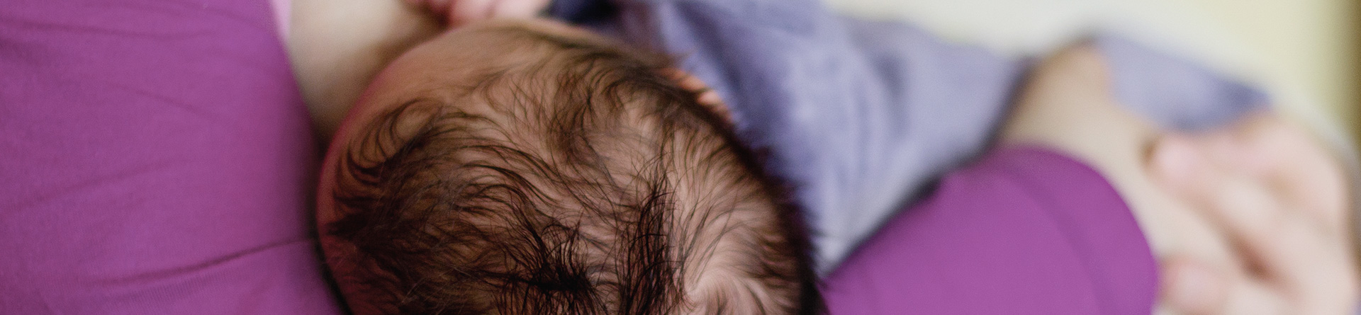 Baby breastfeeding in mother's arms, close-up view.