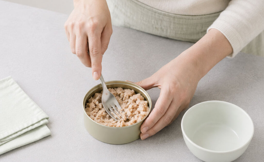 Hands preparing canned tuna with a fork
