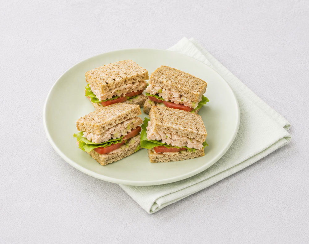 Four small sandwiches on a plate with napkin