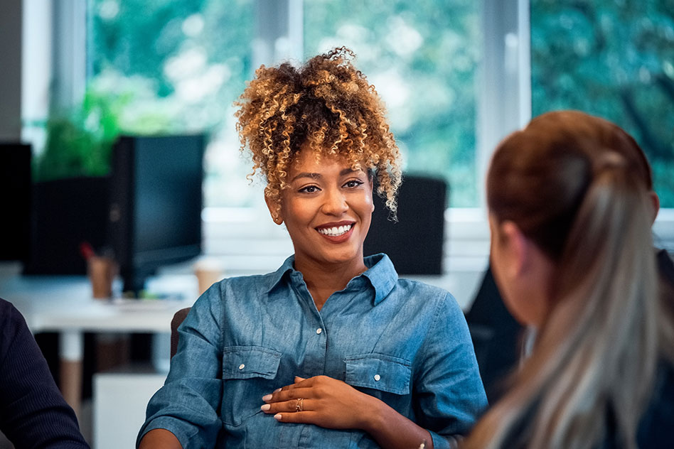 Smiling woman engaging in conversation at an office.