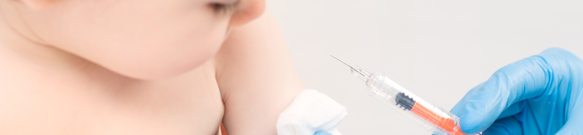 Baby receiving vaccination from gloved hand.