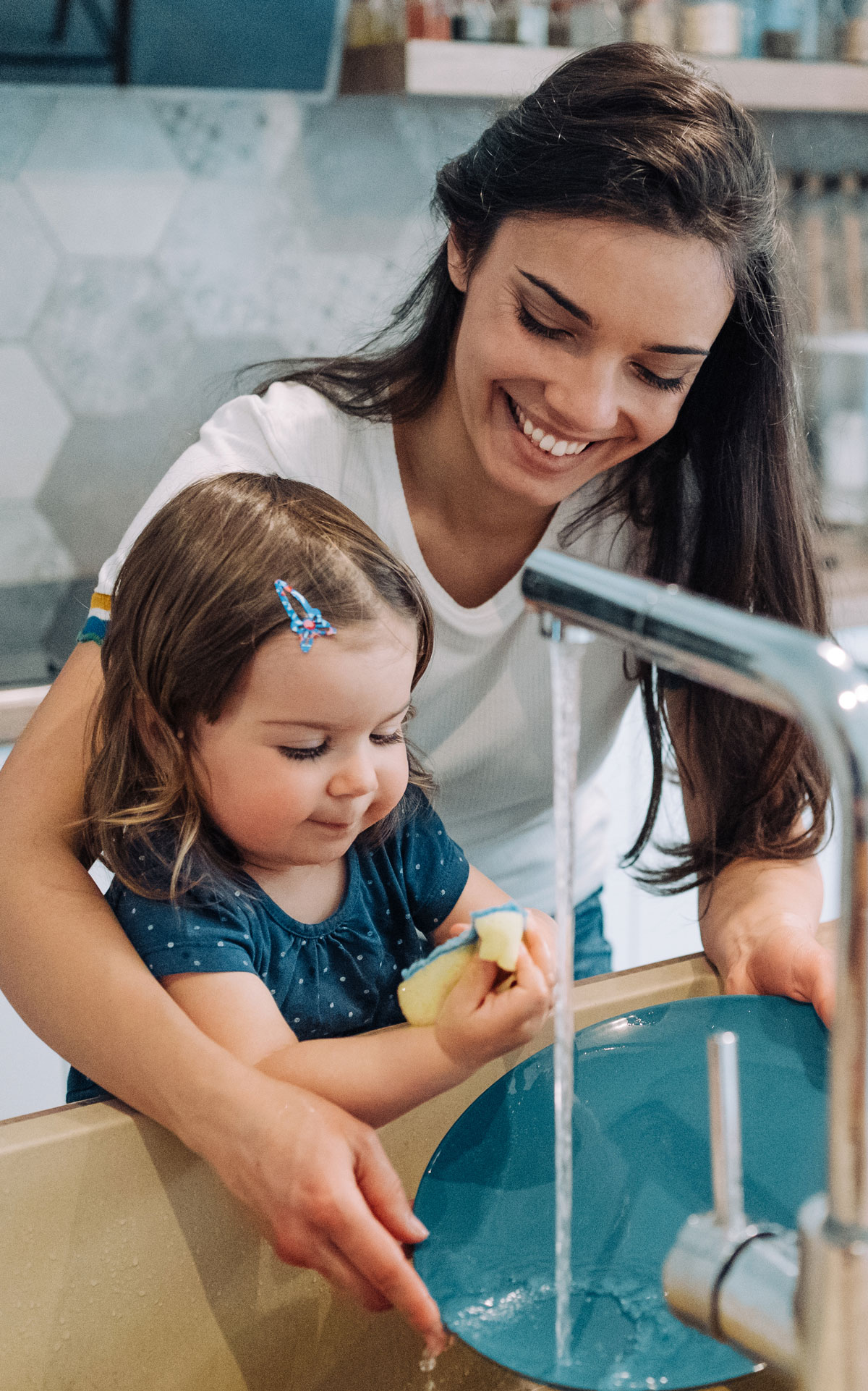 Mother and daughter washing dishes together smiling