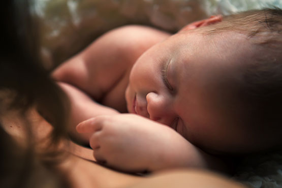 Newborn baby peacefully sleeping on mother's chest