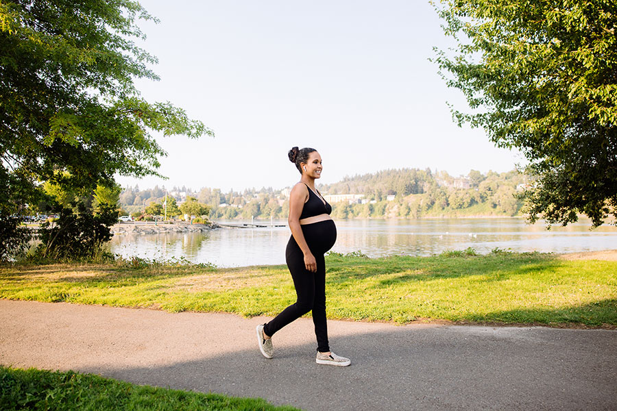 Pregnant woman walking near a sunny lakeside path