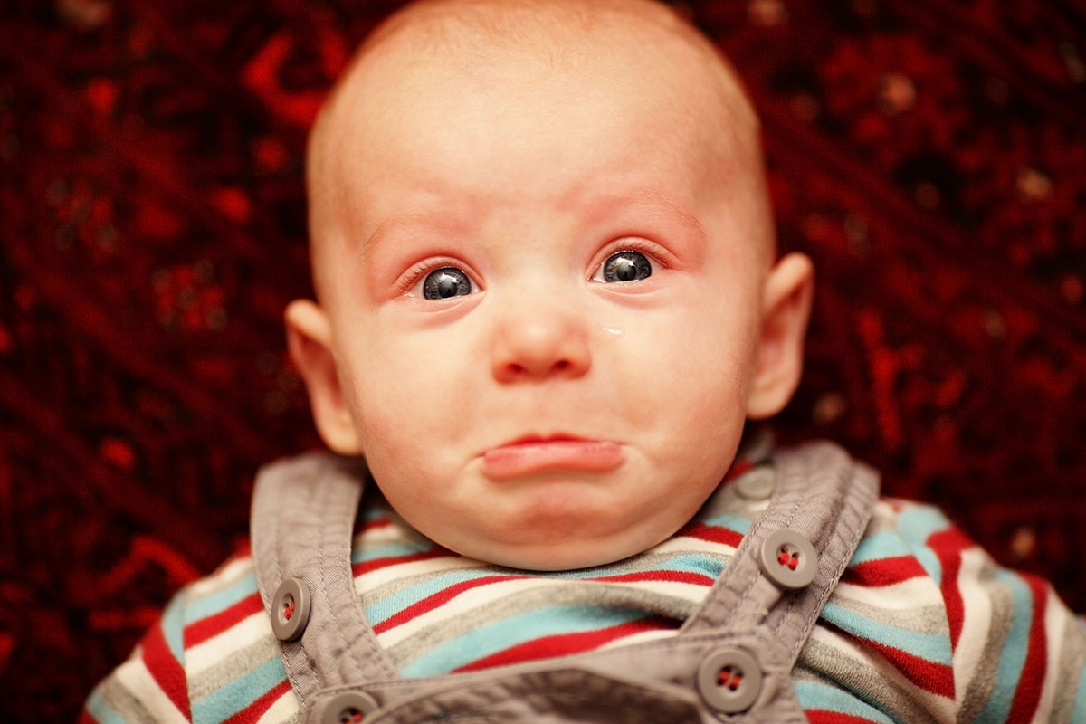 Baby with teary eyes and a sad expression.