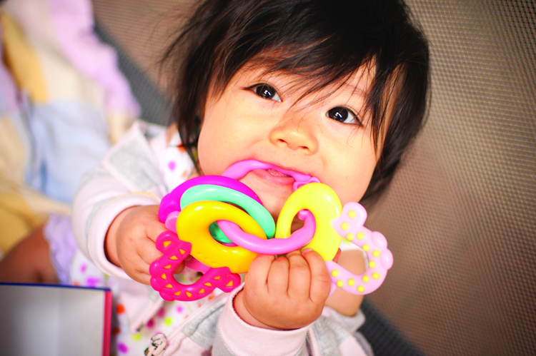 Baby chewing on colorful plastic toy rings