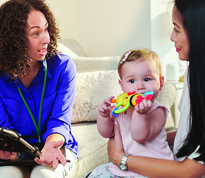 Women discussing while baby plays with toy