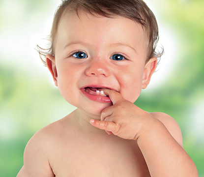Smiling baby with finger in mouth, blurred background